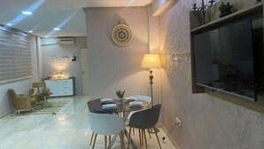 Un soggiorno moderno con zona pranzo, con un tavolo rotondo, sedie, una lampada e un elemento decorativo a parete.
