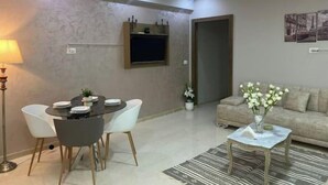 Un soggiorno moderno con angolo pranzo, divano, tavolino e TV a parete.