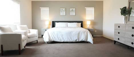 A bedroom with a bed, two bedside tables, a chair, a dresser, and wall art.