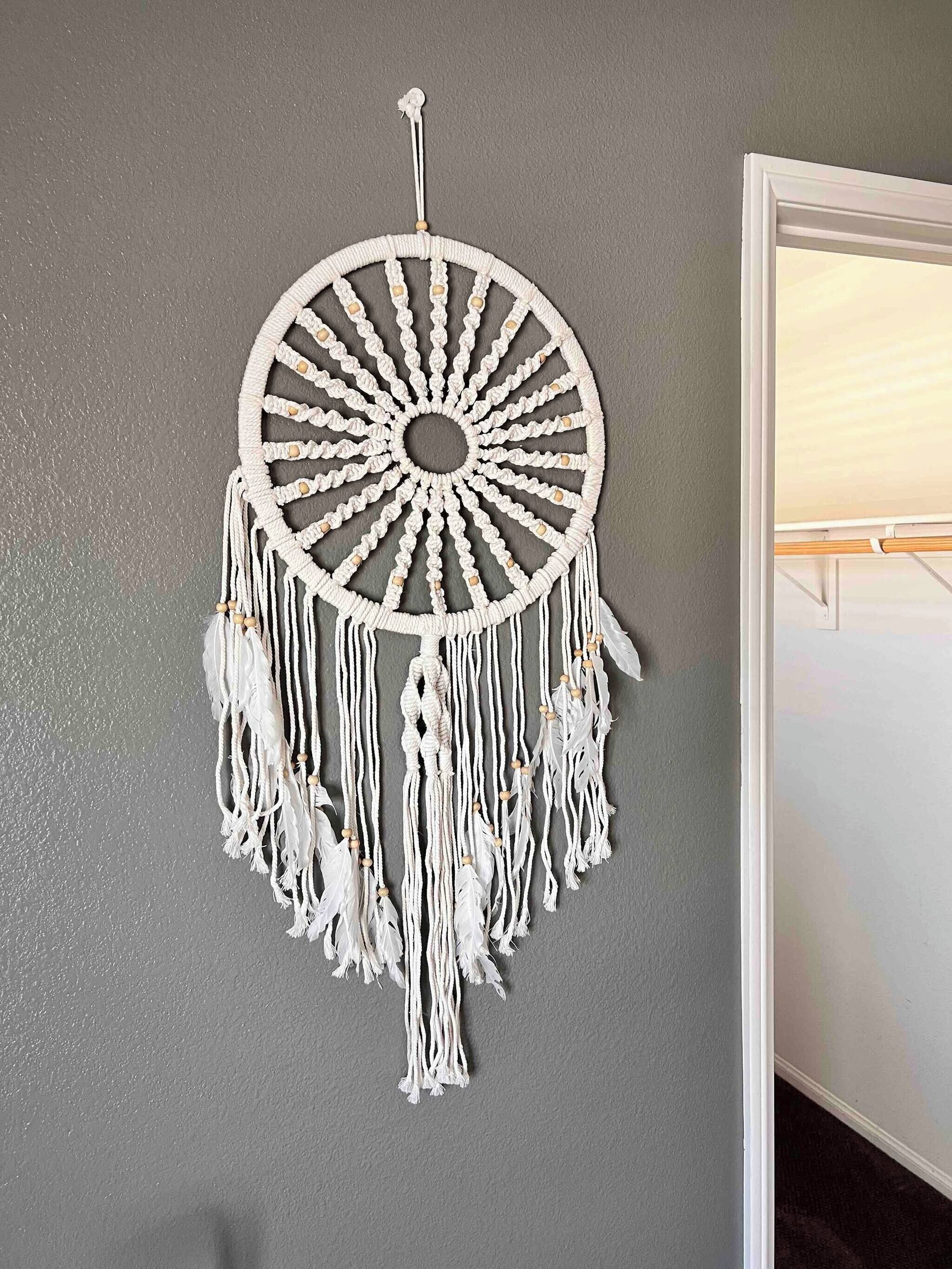 Un colgador de macramé con diseño circular y flecos colgantes.