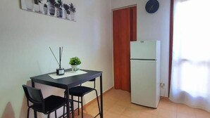 A small kitchen with a refrigerator, a dining table with two chairs, and a ceiling light fixture. - Black Suite With Terrace, sea View Located in the Center (Margherita di Savoia)