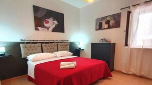 A bedroom with a bed, a hanging light fixture, a painting, and a window with curtains. - Black Suite With Terrace, sea View Located in the Center (Margherita di Savoia)