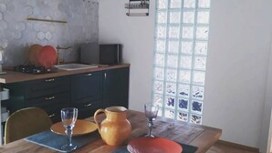 Un comedor con una mesa de madera, sillas, una cocina al fondo y una ventana con vistas.