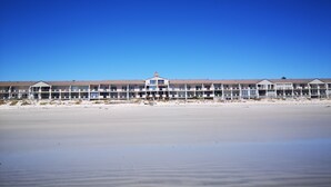 A beachfront hotel with multiple balconies, a central tower, and a sandy beach in the foreground. - Family Cape Town Beachfront Apartment (Cape Town)