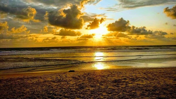 A beach with a sunset, waves, and a cloudy sky. - Splendid Quadruple Room Located 2 Steps From the sea (Margherita di Savoia)