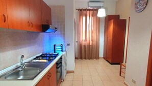 A kitchen with wooden cabinets, a sink, and a stove. - Splendid Quadruple Room Located 2 Steps From the sea (Margherita di Savoia)