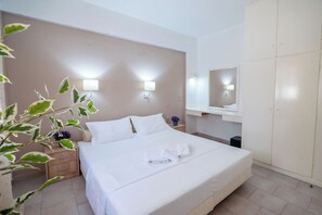 A neatly made bed with white linens, a bedside table with a lamp, a wardrobe, and a wall-mounted mirror. - Corfu Glyfada Menigos 150 (Corfu)