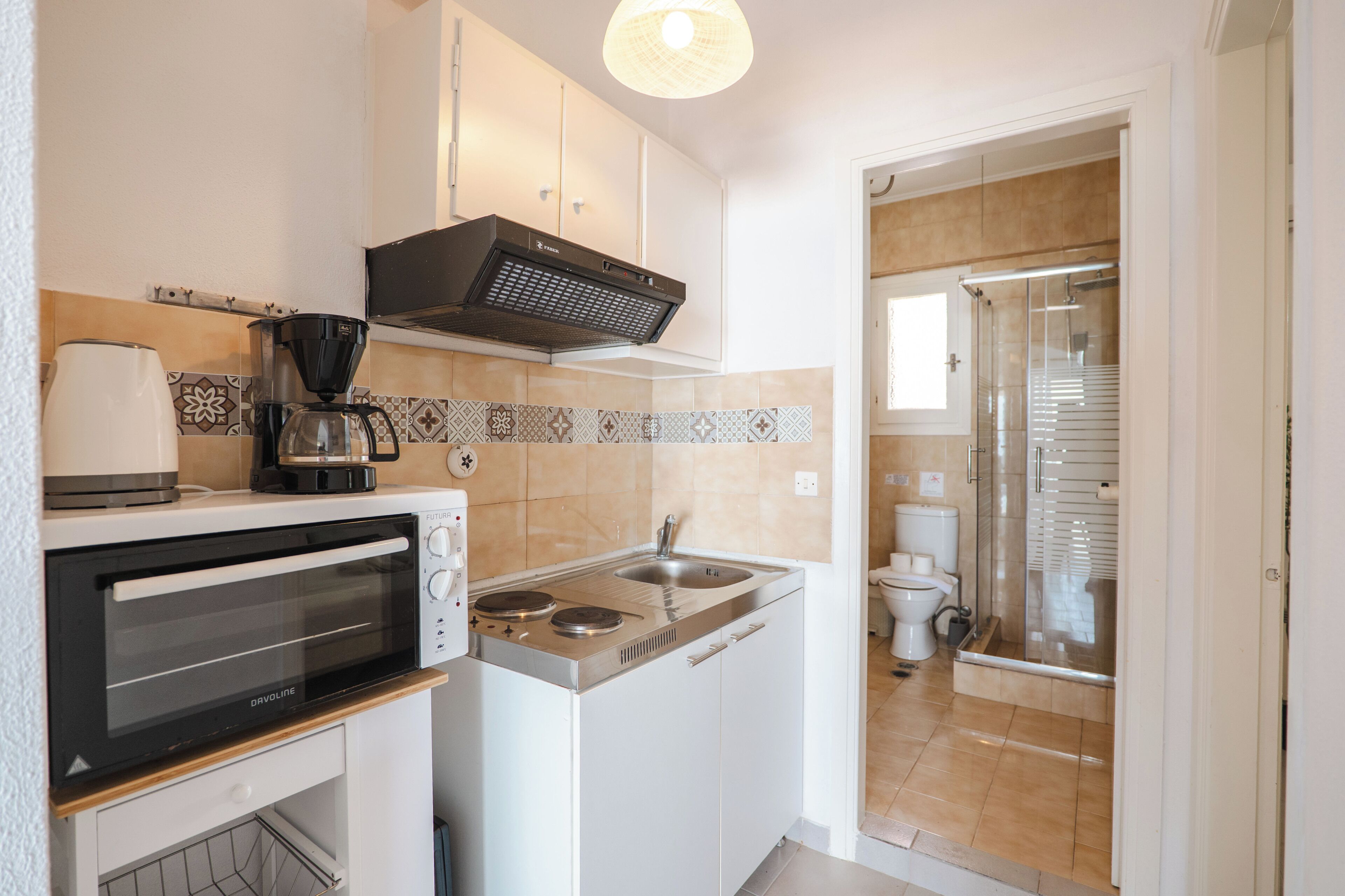 A compact kitchen with a built-in oven, a coffee maker, and a microwave.