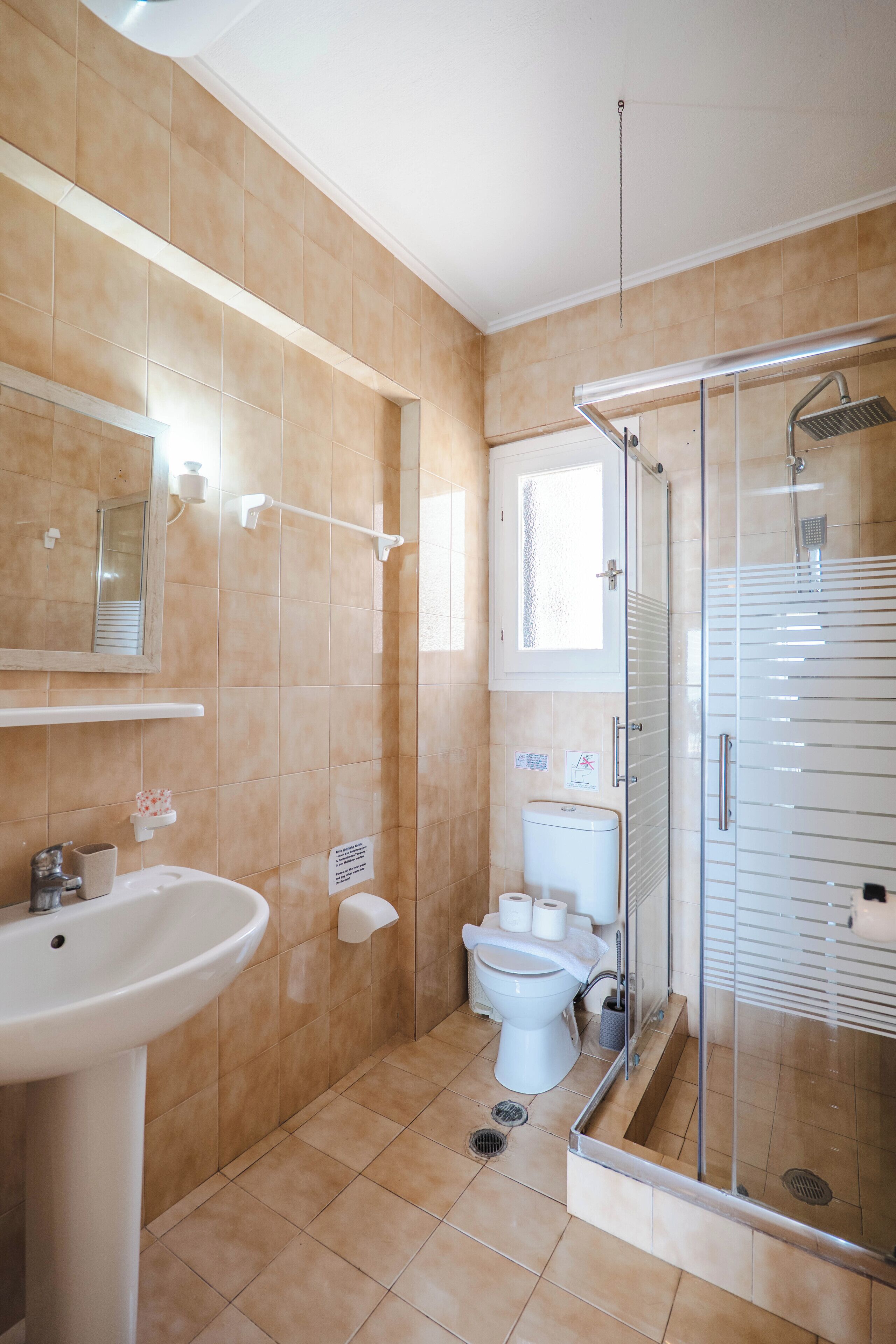 Un baño con lavamanos, inodoro y ducha con mampara de vidrio.