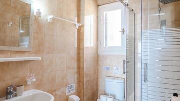Un baño con lavamanos, inodoro y ducha con mampara de vidrio.