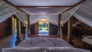Une chambre dotée d’un lit, d’un baldaquin, d’un plancher en bois et offrant une vue sur une piscine extérieure.