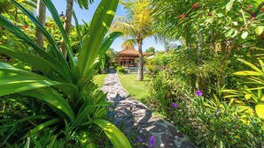 Un sentier de jardin mène à un bâtiment de style traditionnel, surmonté d’un toit en tuiles.