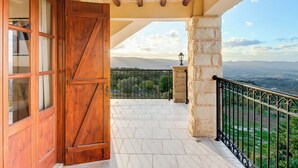 Ein Balkon mit einer Steinsäule, einer Holztür und Blick auf die Landschaft.