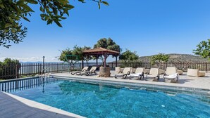Ein klarer, blauer Pool mit Liegestühlen und einem Pavillon.