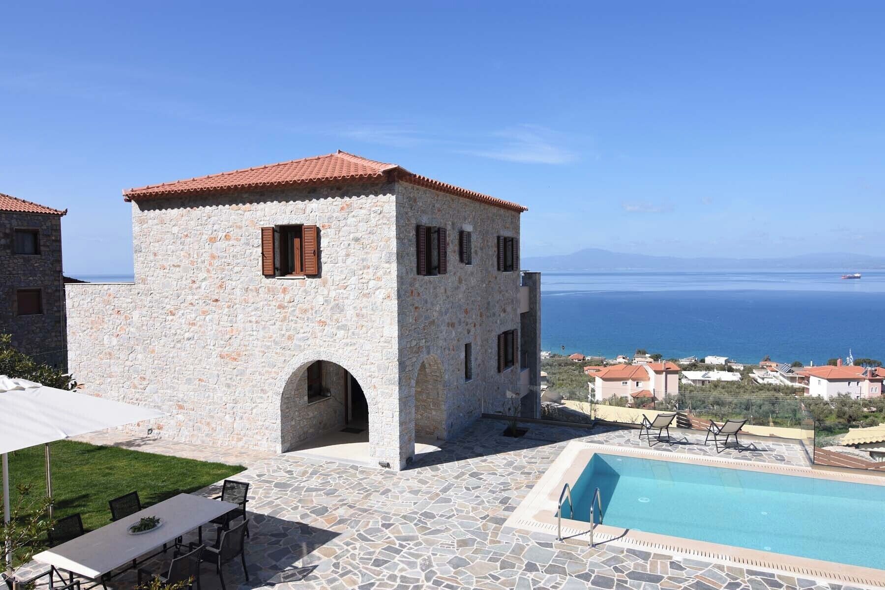 Un bâtiment en pierre doté d’une piscine et d’un espace extérieur aménagé, offrant une vue sur la côte.
