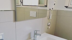 A bathroom with a white sink, a mirror, a hairdryer, and a towel rack. - Room-holiday House the Zagare (Palagiano)
