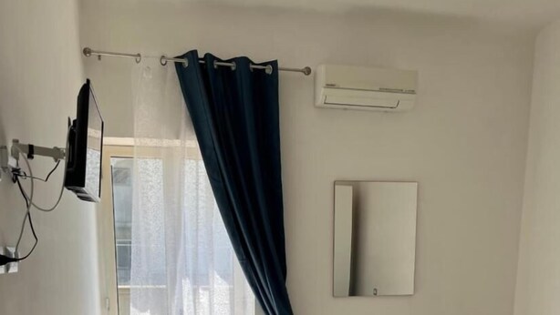 A hotel room with a bed, a desk, a mirror, and a window with curtains. - Room-holiday House the Zagare (Palagiano)