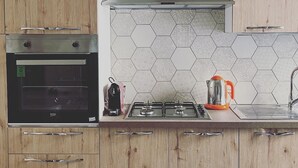 A kitchen with wooden cabinets, a built-in oven, a gas stove, and a hexagonal tile backsplash. - Room-holiday House the Zagare (Palagiano)