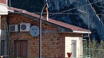 A building with a balcony, satellite dish, and a mountain in the background.