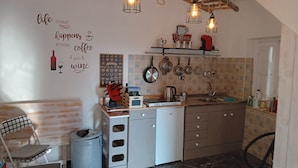 A compact kitchen with a wooden ceiling, hanging light fixtures, and a wall with a coffee-themed decor. - Casa Carolina A Bit Different (Pennadomo)