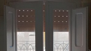 A door with two open panels, revealing a metal gate and a building in the background. - Casa Carolina A Bit Different (Pennadomo)