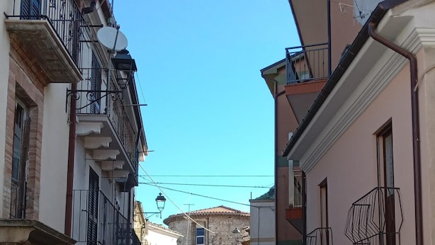 A narrow cobblestone street flanked by buildings with balconies and satellite dishes. - Casa Carolina A Bit Different (Pennadomo)