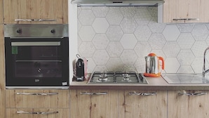 Une cuisine avec des meubles en bois, un four encastré, une cuisinière à gaz et un dosseret de crédence en carreaux hexagonaux.