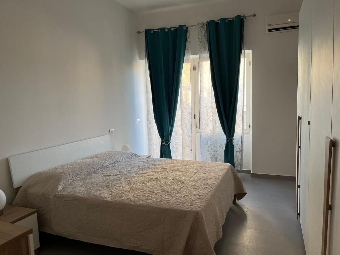 A bedroom with a bed, curtains, and a wardrobe.