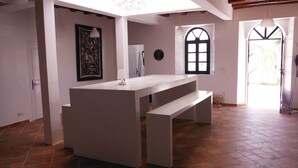 A spacious room with a large white table and benches, a door with a number, and a window with a black frame. - The House Just 8 km From Essaouira and its Beaches (Essaouira)