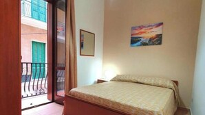 A bedroom with a bed, a window with curtains, a painting on the wall, and a balcony with a view. - Splendid Quadruple in the Center, 2 Steps From the sea (Margherita di Savoia)