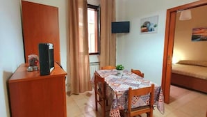 A compact room with a dining table, chairs, a wooden desk, a TV, and a bed. - Splendid Quadruple in the Center, 2 Steps From the sea (Margherita di Savoia)