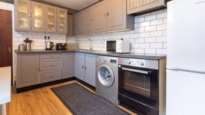 Une cuisine de taille réduite avec des meubles gris, un lave-linge, un four et un four à micro-ondes.