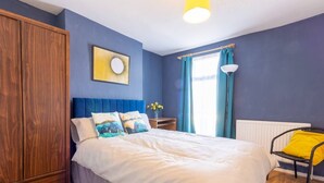 Une chambre à coucher comprenant un lit, une armoire, une table de chevet avec une lampe et une fenêtre avec des rideaux.
