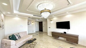 Een ruime woonkamer met een bank, salontafel, televisie en sfeerverlichting.