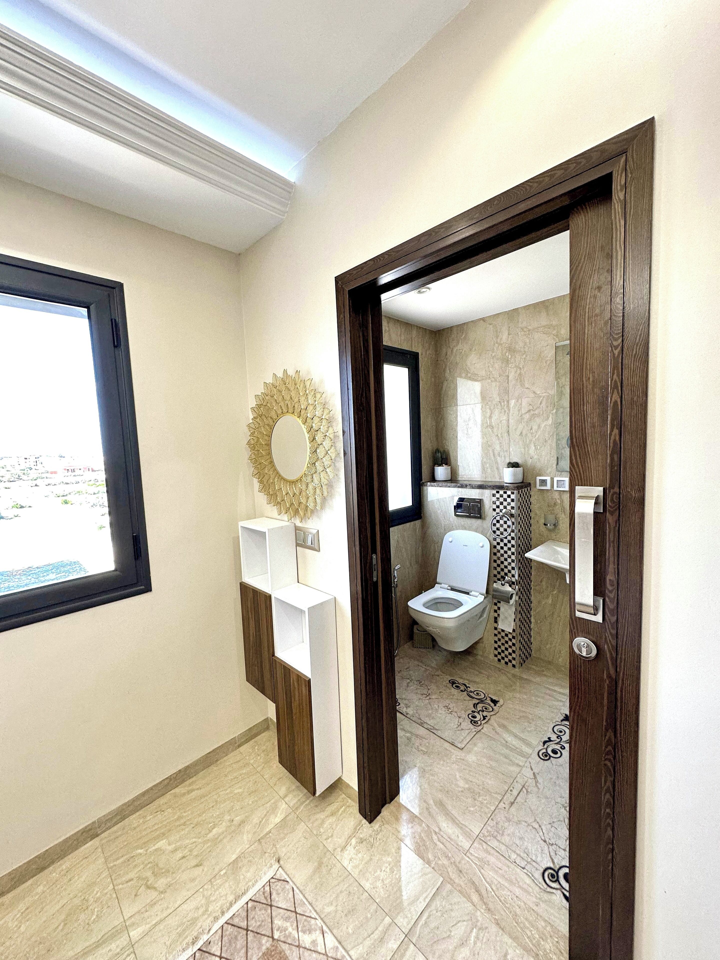 Un baño moderno con inodoro, lavamanos y espejo decorativo.