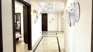 A hotel hallway with marble flooring, wooden doors, and wall art.