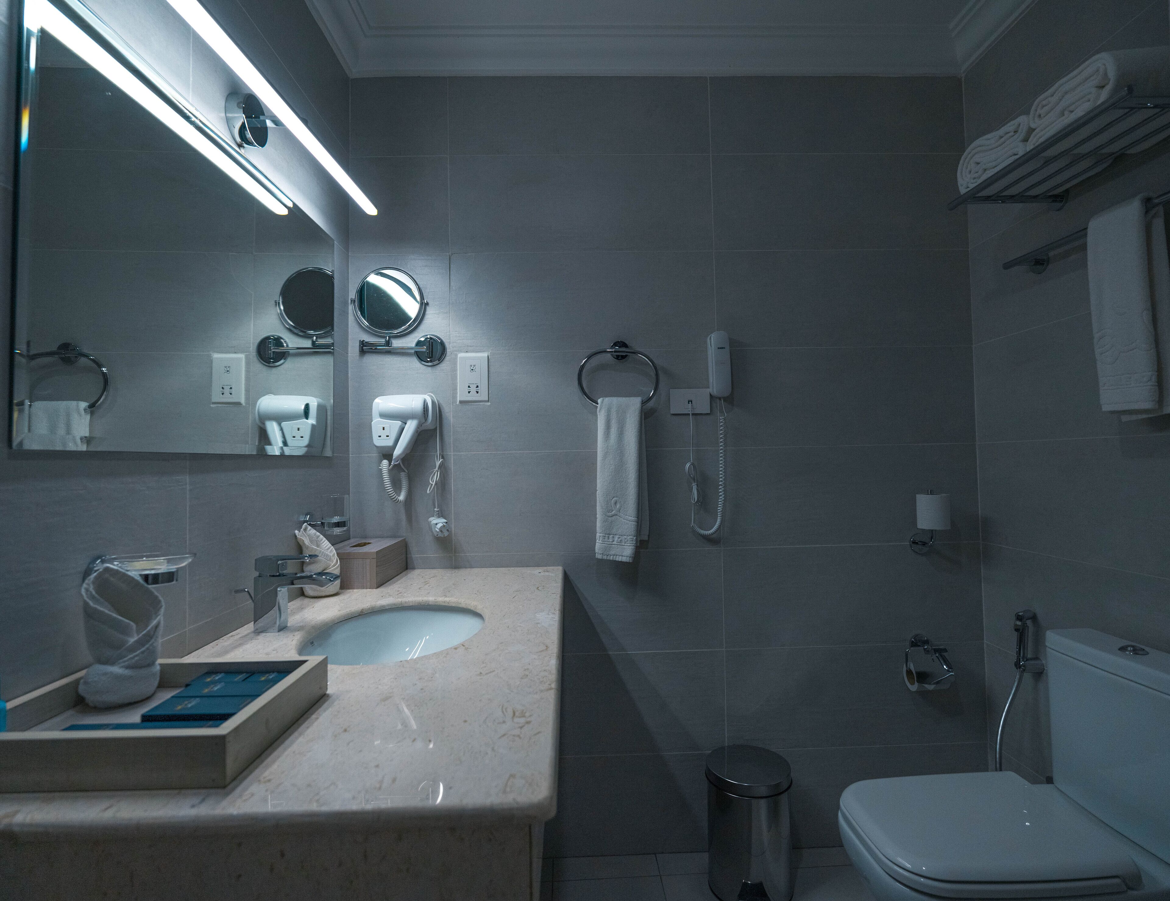 A modern bathroom with a sink, mirror, towel rack, and a toilet.