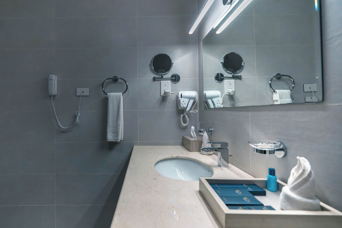 A modern bathroom with a large mirror, a sink, and a towel rack.