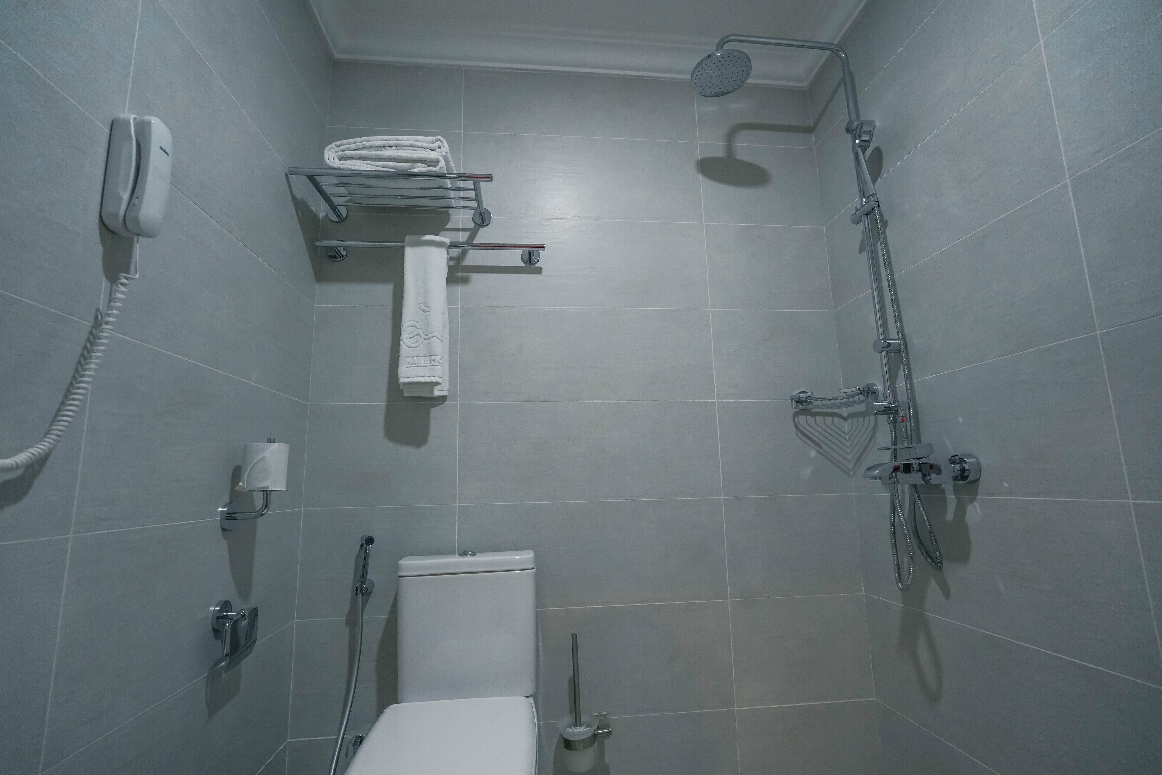 Un baño pequeño y moderno con inodoro, ducha y barra para toallas.