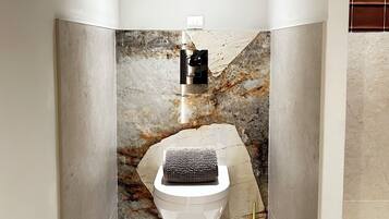 A bathroom with a marble wall, a toilet, a towel, and a toilet paper holder.