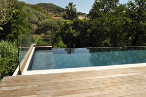 A rectangular swimming pool with a wooden deck, surrounded by lush greenery and trees. - L'Orangeraie d'Afa (Afa)