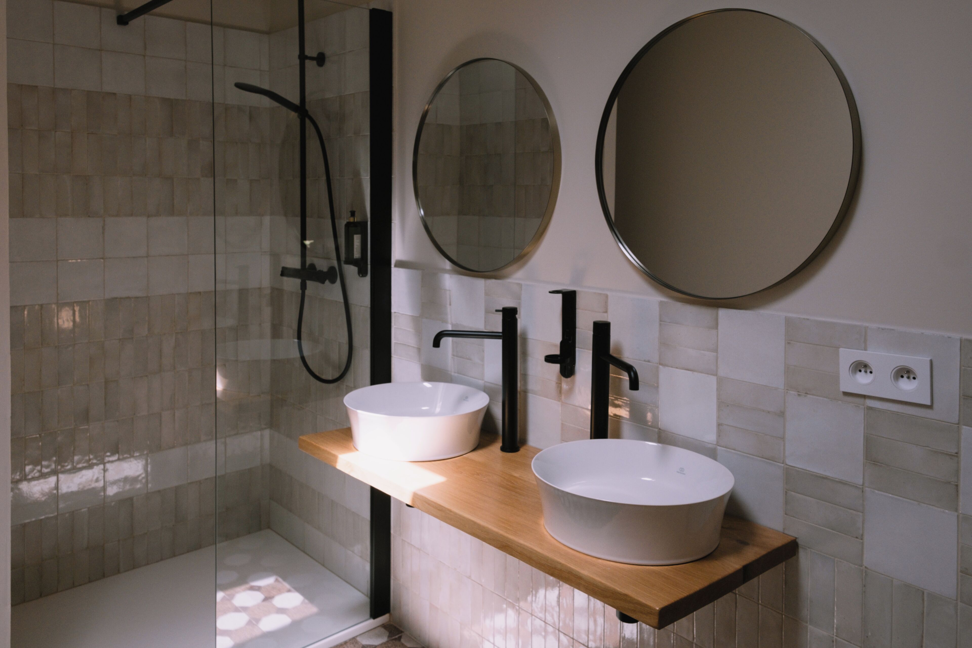 Ein modernes Badezimmer mit zwei Waschbecken, einer Dusche und zwei Spiegeln.