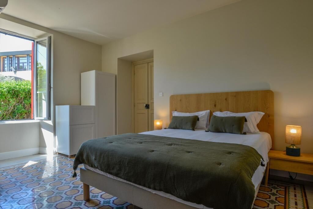 Quarto com cama, luminárias de cabeceira, guarda-roupa e porta que dá para uma varanda.