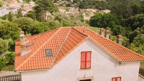 A two-story building with a red-tiled roof, a central entrance with a red door, and a small window on the upper floor. - L'Orangeraie d'Afa (Afa)