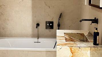 A modern bathroom with a bathtub, a vanity with a marble countertop, and a wall-mounted mirror.