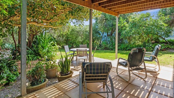 Relax in a serene outdoor space surrounded by lush greenery and a seating area perfect for dining or unwinding.