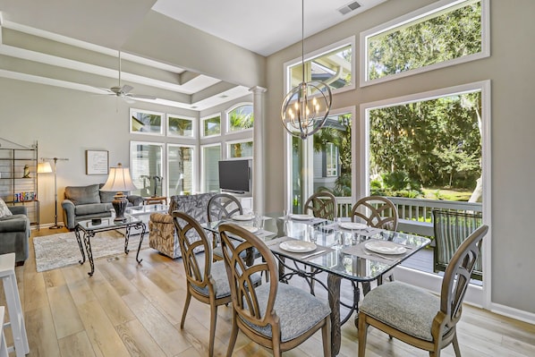 Un salon spacieux avec une grande table à manger, des sièges confortables et une vue sur une végétation luxuriante.