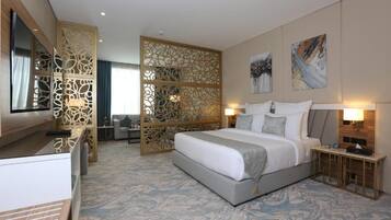 Una habitación de hotel con una cama grande, mesitas de noche, un escritorio y un biombo decorativo.