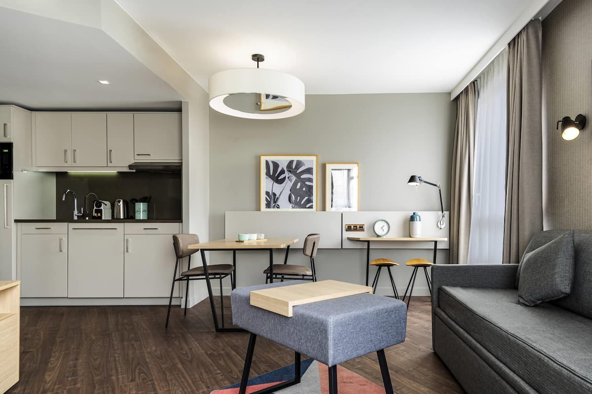 A modern living room with a sofa, a small table, and a dining area with chairs.