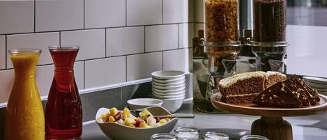 A breakfast buffet with various food items, a coffee machine, and a fruit bowl.